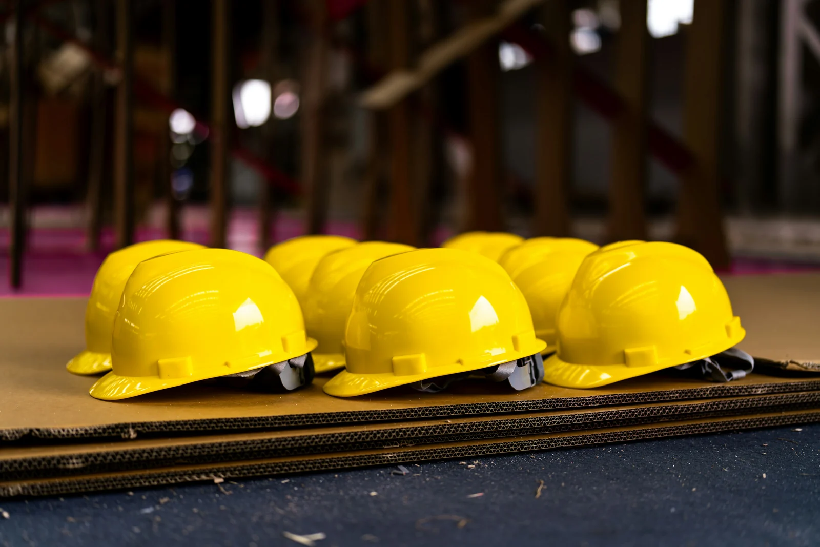 A row of yellow hard hats lined up on a bench